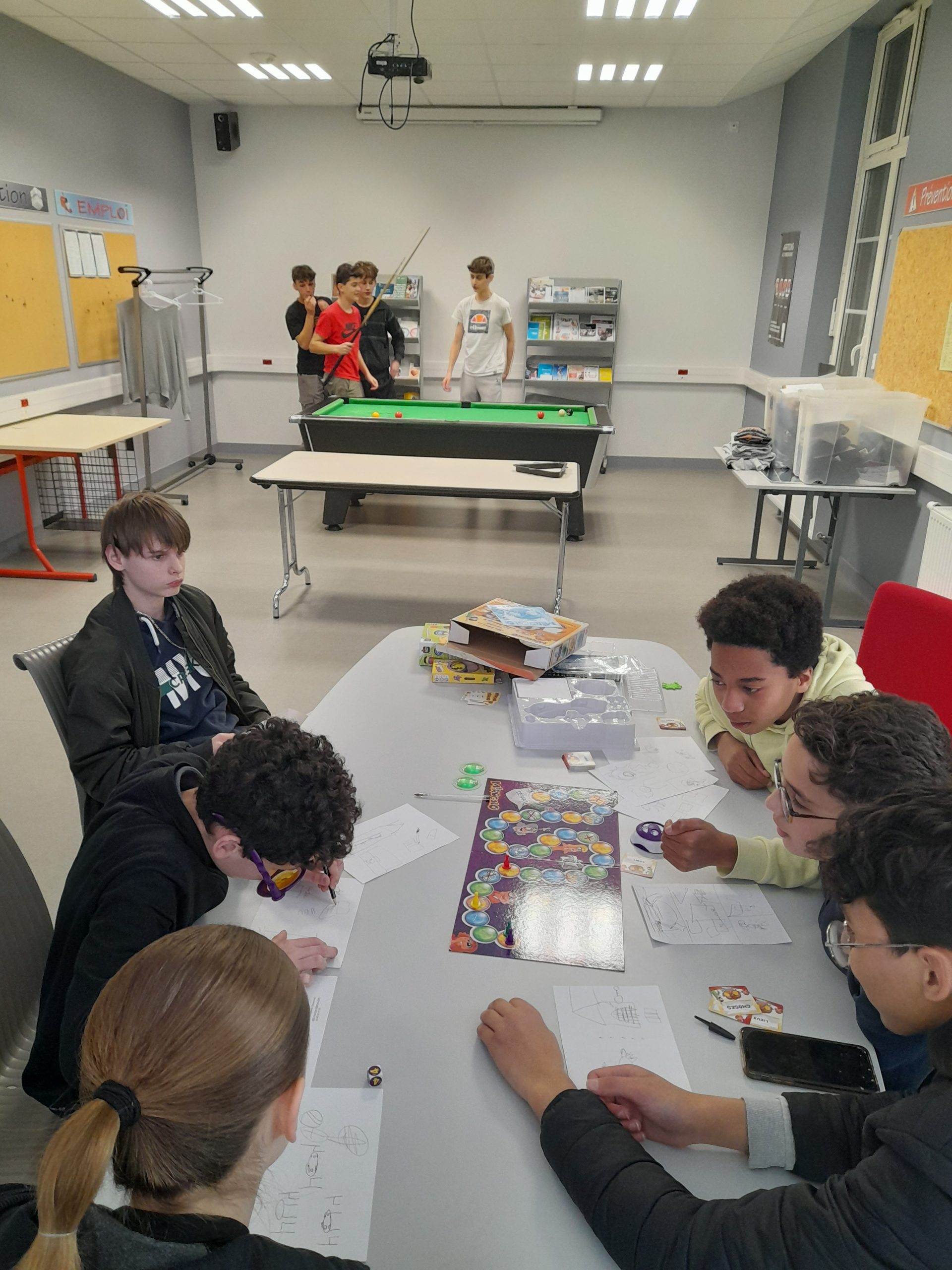 Jeunes ados qui jouent aux jeux de société dans l'espace jeune Jeunes ados qui jouent aux jeux de société dans l'espace jeune